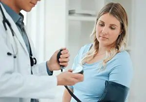 Gauge Prints: a doctor using a blood pressure gauge during a checkup with his pregnant patient
