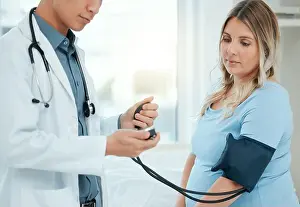 Gauge Prints: a doctor using a blood pressure gauge during a checkup with his pregnant patient