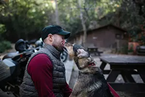 Licking Prints: Dog licking man face while sitting in forest