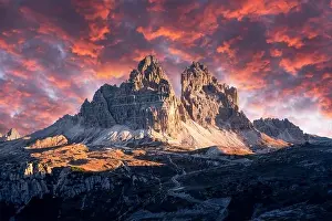 Dramatic evening landscape with Three peaks of Lavaredo mountains, glowing road and pink sunset sky