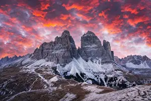 Dramatic evening landscape with Three peaks of Lavaredo mountains, glowing road and pink sunset sky