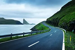 Dramatic evening view of the road and the Drangarnir and Tindholmur rocks in the background on the island of Vagar, Faroe Islands, Denmark