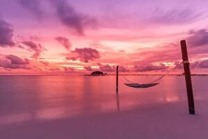 Images Dated 22nd October 2019: Dramatic sunset sky in tropical island beach. Swing or hammock over water