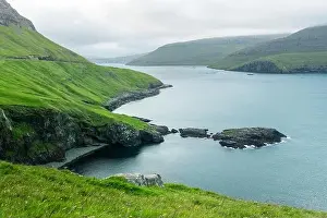Dramatic view of green hills of Vagar island and Sorvagur town on background. Faroe islands, Denmark. Landscape photography