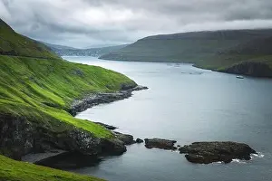 Dramatic view of green hills of Vagar island and Sorvagur town on background. Faroe islands, Denmark. Landscape photography