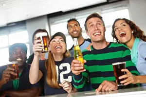 Cheering Prints: Drinks on me if we win. A group of friends cheering on their favourite team at the bar