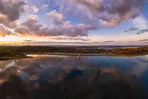 Drone aerial view of a lake reservoir of a dam with perfect reflection on the water of the sunset in Sabugal, Portugal