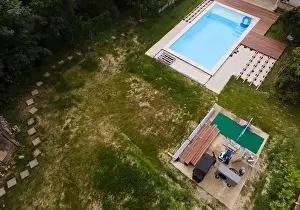 Above View Prints: Drone flight over beautiful green garden with pool and the wooden terrace of the pool is currently in progress