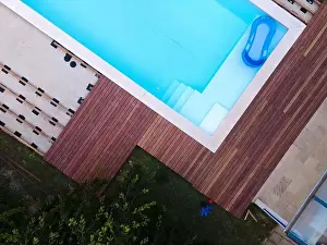 Above View Prints: Drone flight over beautiful green garden with pool and the wooden terrace of the pool is currently in progress