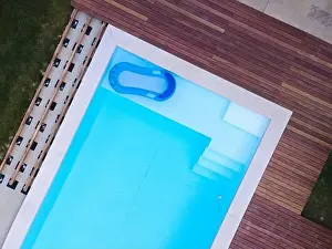 Above View Prints: Drone flight over beautiful green garden with pool and the wooden terrace of the pool is currently in progress