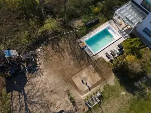 Drone flight over fresh earth area with grass grown next to pool construction site in April