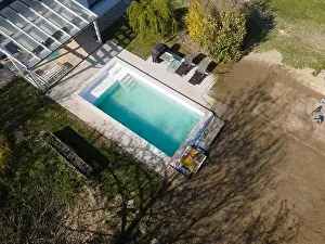 Drone flight over fresh earth area with grass grown next to pool construction site in April