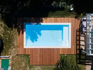 Above View Prints: Drone flight over pool with nice wooden terrace surrounded by green lawn in beautiful garden