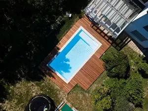 Above View Prints: Drone flight over pool with nice wooden terrace surrounded by green lawn in beautiful garden