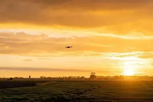 Beauty Of Nature Prints: A drone flying over green springtime meadows with a colorful orange sunset sky behind