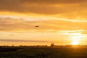 Beauty Of Nature Prints: A drone flying over green springtime meadows with a colorful orange sunset sky behind