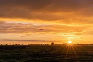 Beauty Of Nature Prints: A drone flying over green springtime meadows with a colorful orange sunset sky behind