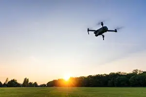 Hovering Prints: Drone flying over landscape. UAV drone copter flying with digital camera