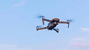 Hovering Prints: Drone flying over landscape. UAV drone copter flying with digital camera