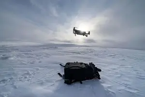 Drone flying into winter sun over the snowy hills of Urho Kekkonen National Park, Saariselka, Inari, Lapland, Finland