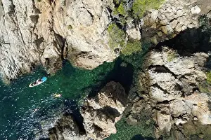 Drone photo looking down on swimmers in a rocky Cove in the South of France