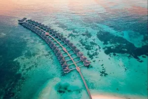 Drone photo wooden water villas seen from above and an amazing blue lagoon crystal clear water close to tropical lagoon. Amazing summer
