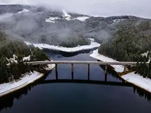 Drone photography from a high altitude of a road and a bridge crossing a mountain lake
