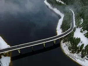 Forest Trees Prints: Drone photography from a high altitude of a road and a bridge crossing a mountain lake