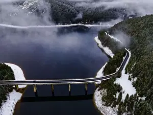 Drone photography from a high altitude of a road and a bridge crossing a mountain lake