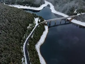 Drone photography from a high altitude of a road and a bridge crossing a mountain lake