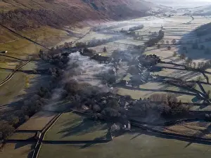 Geological Formation Prints: Drone shot shows morning Mist and smoke from a chimney float above yorkshire dales village of arncliffe