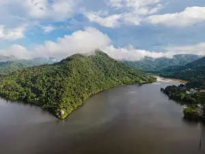 Thicket Prints: Drone view of calm winding lake streaming through hilly valley covered with dense forest and clouds
