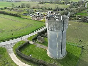 Ariel Prints: Drone view of a concrete water tower which has an array of 5G antennas on its circular roof