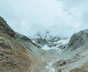 Mountain Ridge Prints: drone view over a desolate receding alpine glacier surrounded by mountains and snow covered rocks and peaks