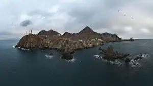 Navigate Prints: Drone view of lighthouse located on rough cliff near sea under cloudy sky in Almeria