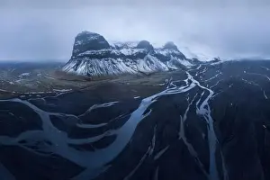 Drone view of magnificent rocky snowy Lomagnupur Mountain slope in cloudy sunset sky in Iceland