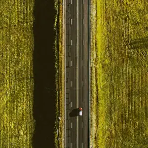 Top Drive Prints: Drone view of moving red car on country side road with beautiful green field around