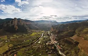 Drone view of scenic grassy mountain slopes and fields with infrastructure in valley