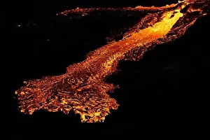 Drone view of stream of hot orange lava flowing through mountainous terrain in morning in Iceland