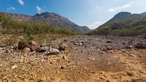Vastness Prints: Dry rocky valley with scattered stones and shrubs
