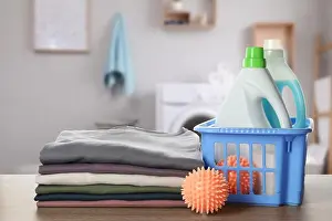 Housewife Prints: Dryer balls, detergents and stacked clean clothes on wooden table in laundry room