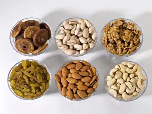 Pistachio Prints: Dryfruits and nuts in six bowls shot against a white background
