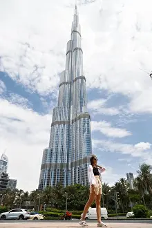 Burj Khalifa Prints: DUBAI, UAE. A happy young woman enjoys the view in front of the Burj Khalifa