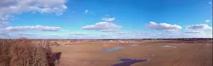 Early spring time farmland fields panorama with groves and puddles, aerial view