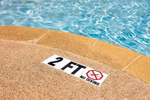 Edge of swimming pool with NO Diving warning sign and 2 ft depth marker