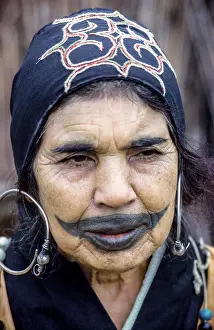 Verticals Prints: An elderly Ainu woman shows off a childhood tattoo on her face outside her village home in 1962 on the island of