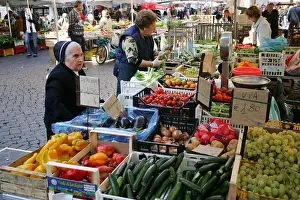 Elderly Italian Catholic Nun in traditional black habit buys fresh fruit vegetables colourful market stall central Rome