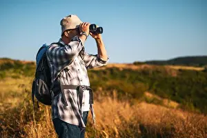Backpacker Prints: Elderly man standing in sunny forest scenery