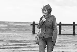 Middle Aged Woman Prints: Elderly / Middle aged woman walking by the sea on the coast on a windy day in the UK