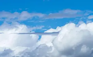 The electric blue sky is adorned with fluffy white cumulus clouds
